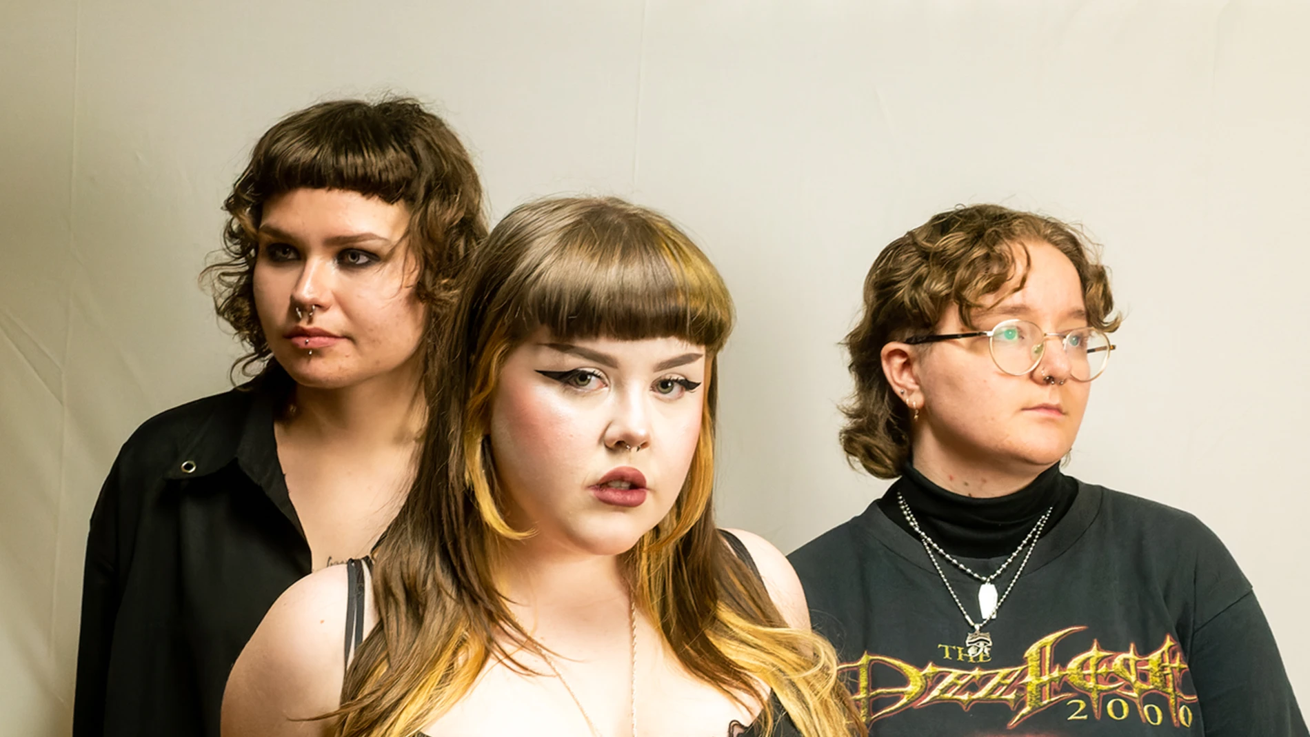 Picture Perfect: How To Prepare For A Portrait Photoshoot 1 Three Individuals With Distinctive Hairstyles And Piercings Against A Plain Backdrop.