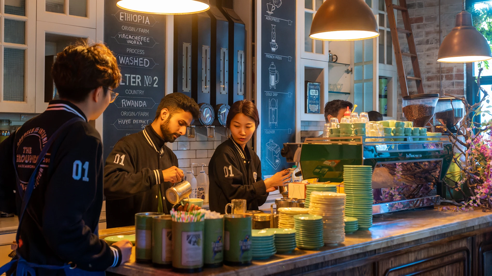Visualising Success: Why Small Businesses Need Professional Photographers 1 Baristas Make Coffee At A Counter With Green Cups And Equipment, Menu Visible On The Wall.