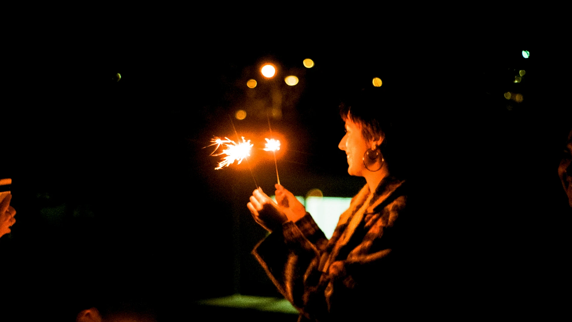 The Resurgence Of Film Photography: A Timeless Art In The Digital Age 1 Person Holding Sparklers In The Dark, With Blurred Lights In The Background.