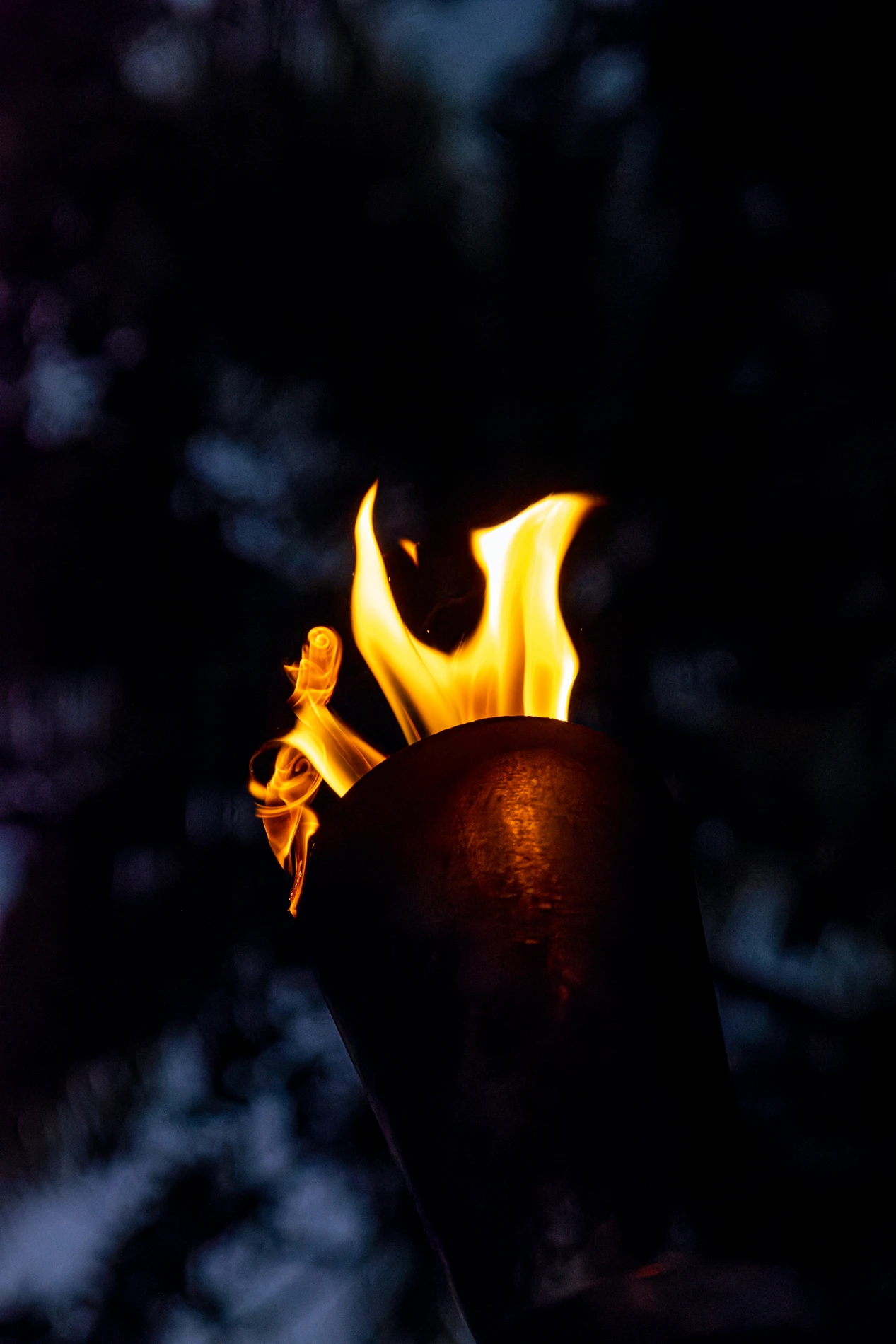 Lit Torch With Vibrant Flame Against A Dark, Blurred Background.