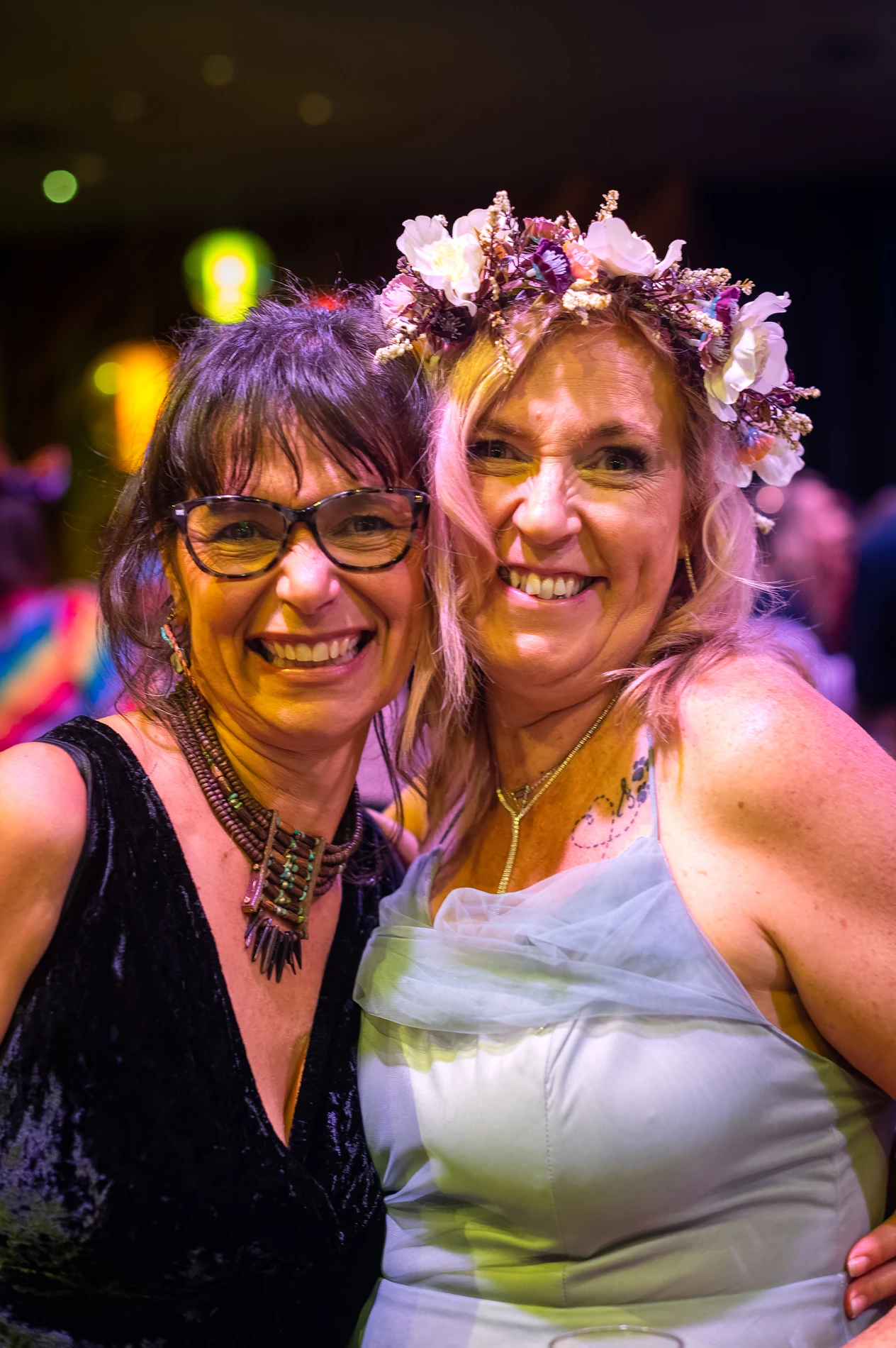 GalleriesWonenIllawarraFundraiserLilliAndNicTwoWomenSmiling Two Women Smiling At An Indoor Event, One In Glasses And Dark Dress, The Other In Floral Headpiece.