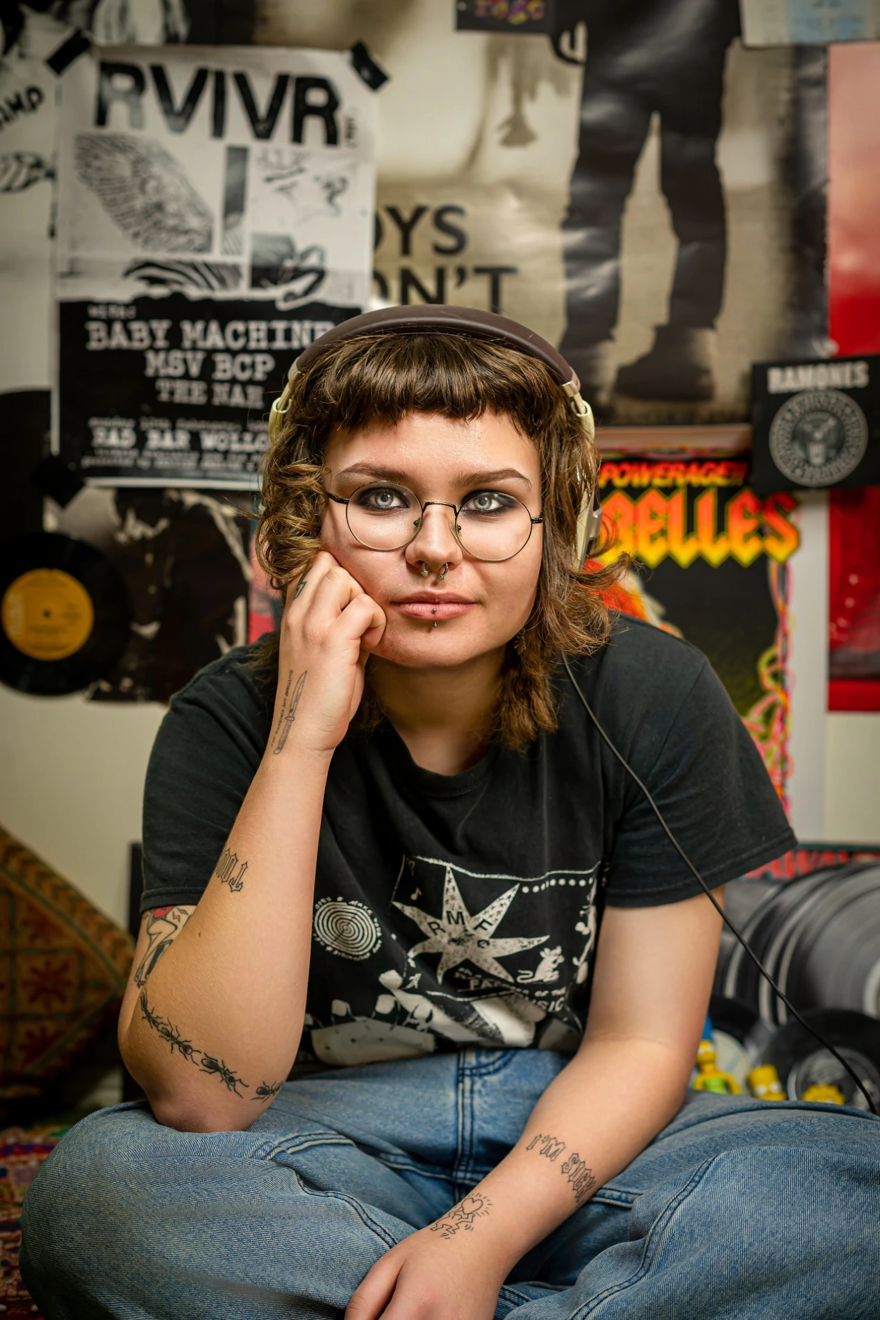 Person With Glasses And Headphones In A Room With Band Posters And Vinyl Records.